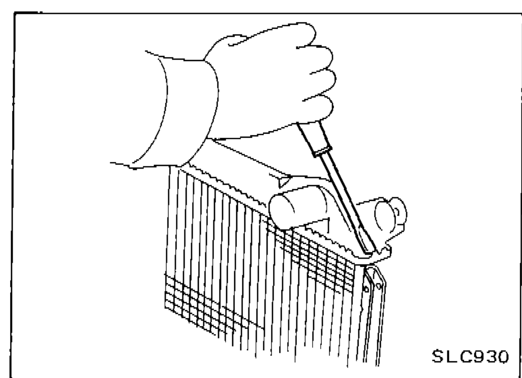 Hand using a screwdriver to bend the edge of the radiator tank up