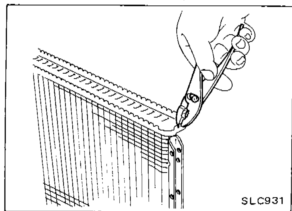 Hand using a tool to straighten the edge of the radiator tank; edge stands straight up