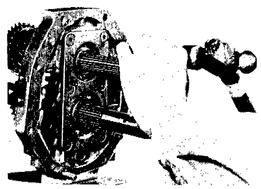 Photograph showing staking of bearing retainer screws at two points on the adapter plate assembly.