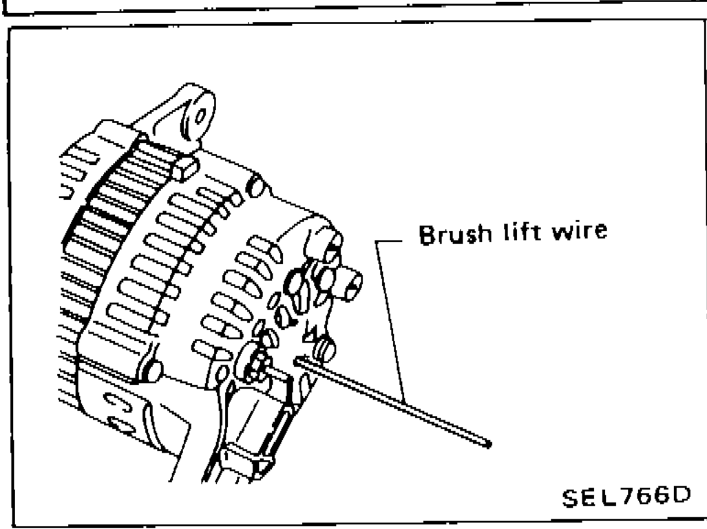 Alternator rear cover installation showing brush lift wire being inserted into brush lift hole from outside