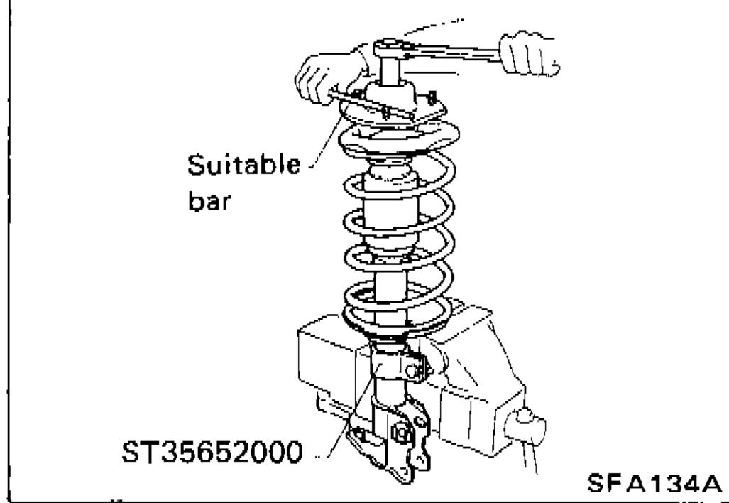 Strut assembly set on vise with Tool ST35652000 and suitable bar to loosen piston rod lock nut