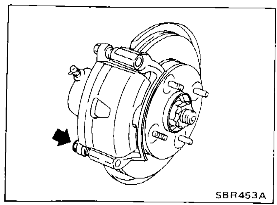 Front caliper viewed from rear with arrow pointing to lower pin bolt being removed.
