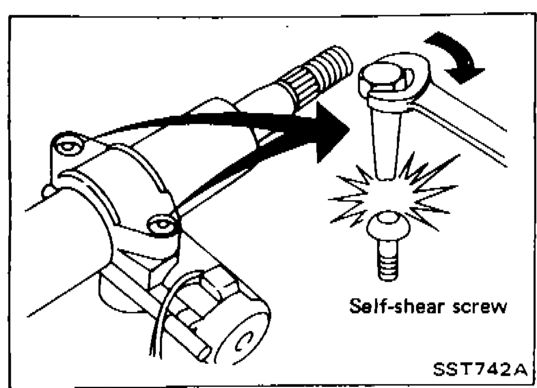 Drill bit drilling out a self-shear-type screw on the steering-lock housing; broken-screw debris shown next to the housing.