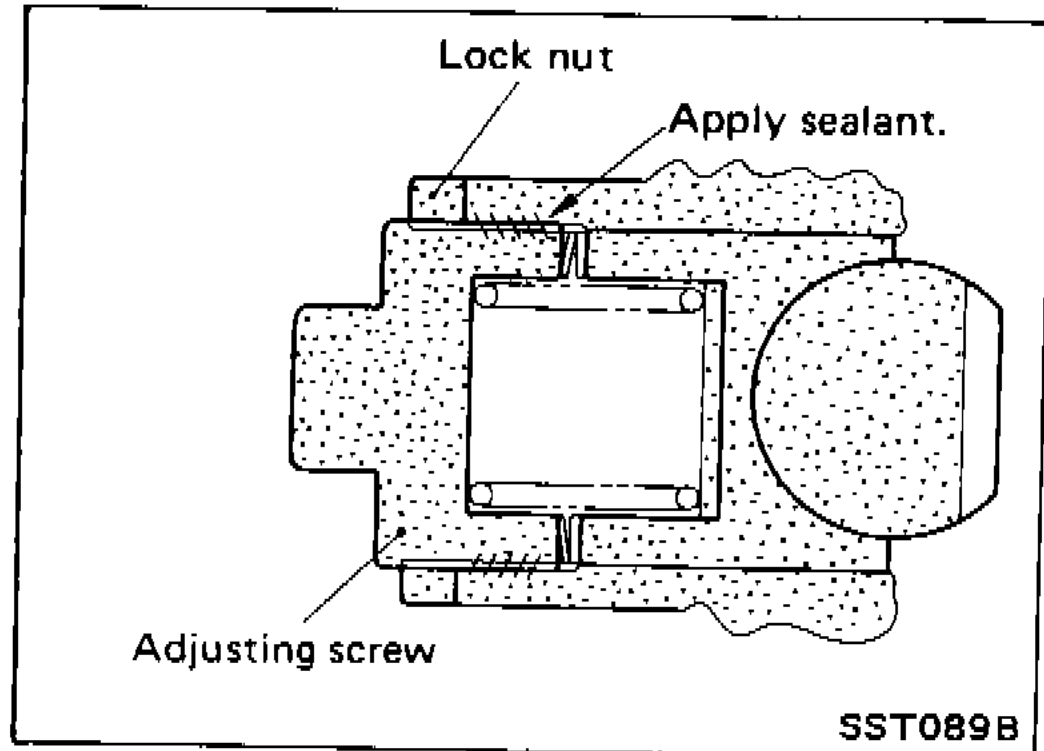 Adjusting screw at top of pinion housing with locking sealant being applied; lock nut shown above.
